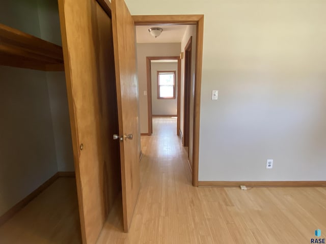 hallway with light wood-style flooring and baseboards