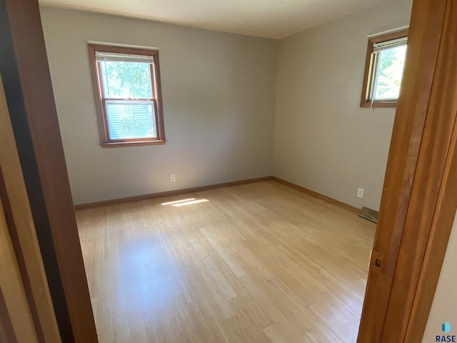 unfurnished room with a healthy amount of sunlight, light wood finished floors, and baseboards