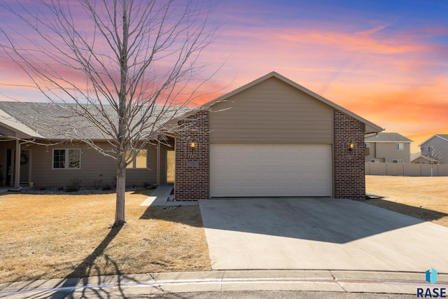 view of front of property with a garage, a lawn, concrete driveway, fence, and brick siding