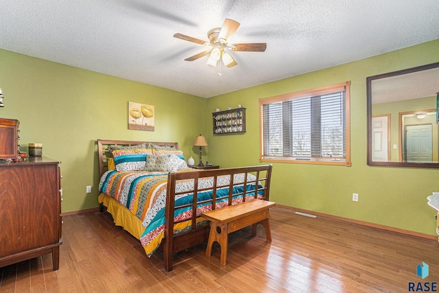 bedroom featuring a textured ceiling, wood finished floors, visible vents, and baseboards