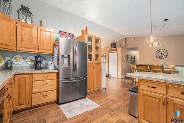 kitchen featuring light countertops, stainless steel fridge, lofted ceiling, and light wood finished floors