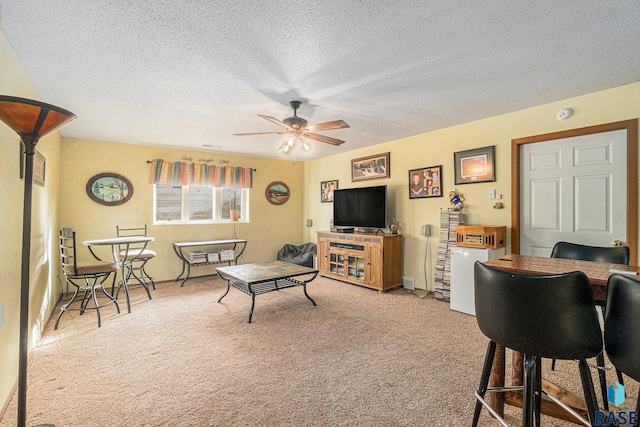 carpeted living room with a ceiling fan and a textured ceiling