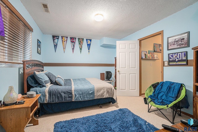 carpeted bedroom featuring a textured ceiling and visible vents