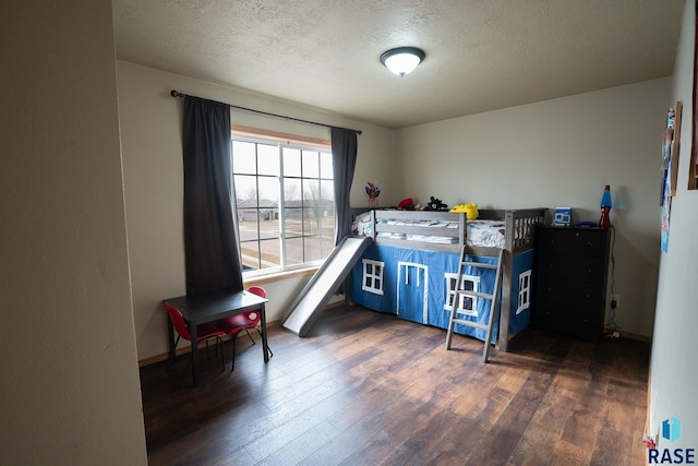 bedroom with a textured ceiling, wood finished floors, and baseboards