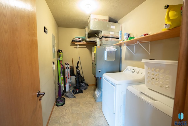 clothes washing area with laundry area, electric panel, a textured ceiling, and washing machine and clothes dryer