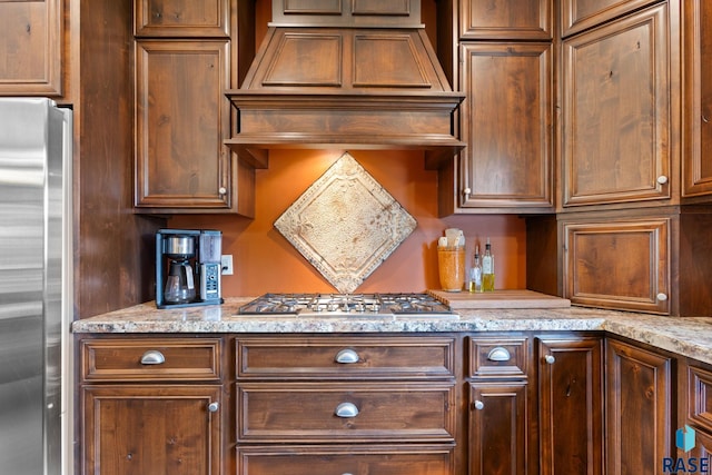 kitchen with custom range hood, light stone counters, and stainless steel appliances