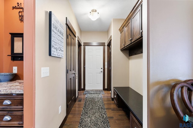 mudroom featuring dark wood-style flooring and baseboards