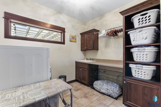 washroom featuring washer / dryer, cabinet space, a sink, and baseboards