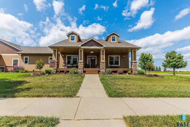 craftsman inspired home with covered porch, stone siding, and a front lawn