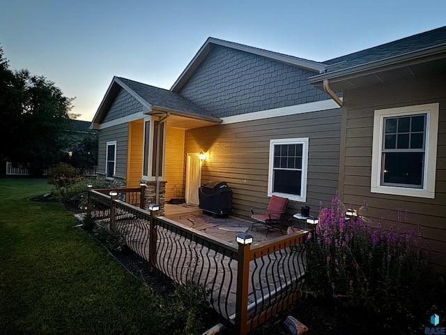 back of house featuring a shingled roof and a lawn