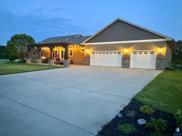 craftsman-style house with a front yard, stone siding, driveway, and an attached garage