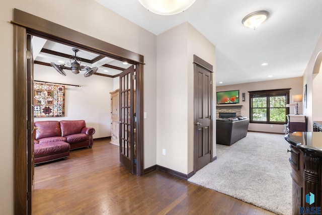 hallway with baseboards, coffered ceiling, beamed ceiling, wood finished floors, and recessed lighting