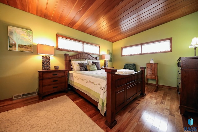 bedroom with vaulted ceiling, multiple windows, wood finished floors, and visible vents