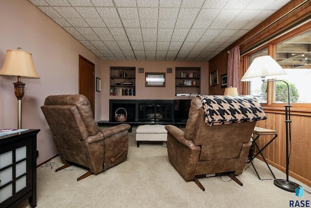 living area featuring built in shelves, carpet flooring, and wood walls