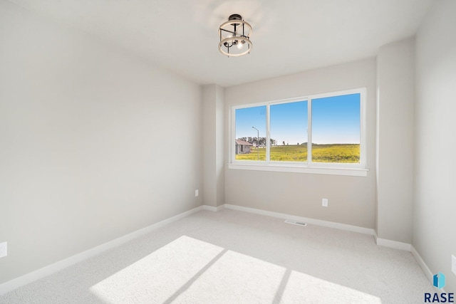 spare room with light colored carpet, visible vents, and baseboards