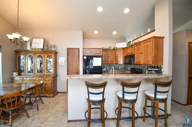 kitchen with a notable chandelier, a peninsula, black appliances, tasteful backsplash, and brown cabinetry