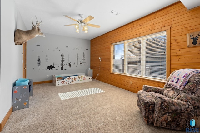 recreation room with ceiling fan, wood walls, carpet flooring, and visible vents