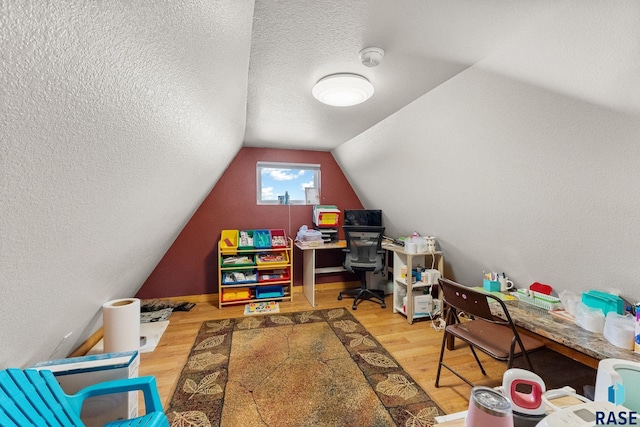 rec room featuring a textured ceiling, vaulted ceiling, and wood finished floors