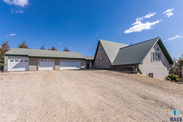 view of side of property with a garage, metal roof, and dirt driveway