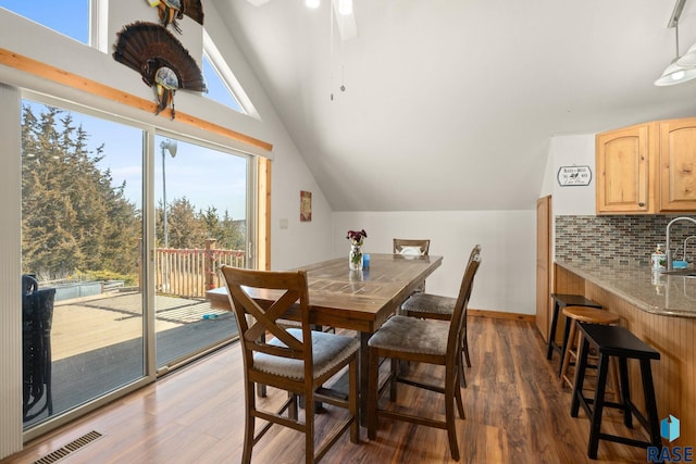 dining area featuring dark wood-style floors, lofted ceiling, visible vents, and baseboards