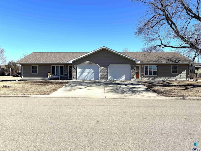 ranch-style house featuring an attached garage, driveway, and a shingled roof