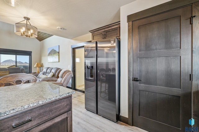 kitchen with lofted ceiling, open floor plan, dark brown cabinets, stainless steel fridge with ice dispenser, and light wood finished floors