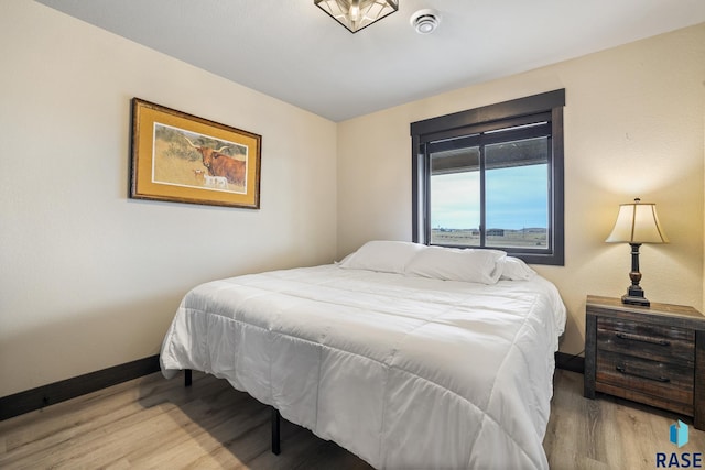 bedroom with baseboards and wood finished floors