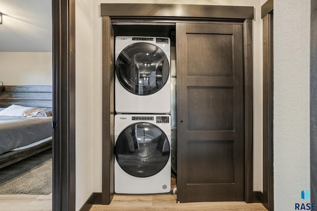 washroom with stacked washer and dryer, wood finished floors, and laundry area