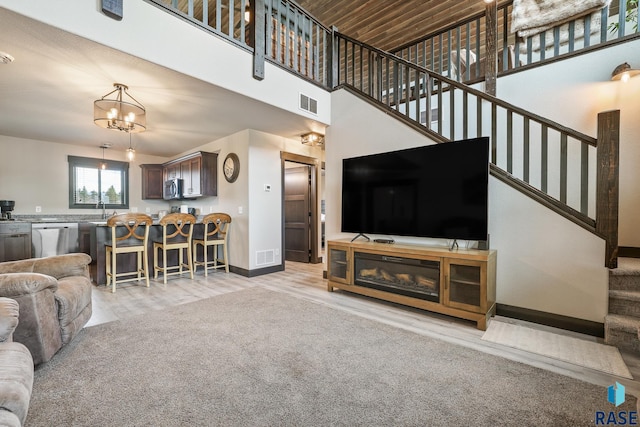 living area with baseboards, visible vents, stairway, and a high ceiling