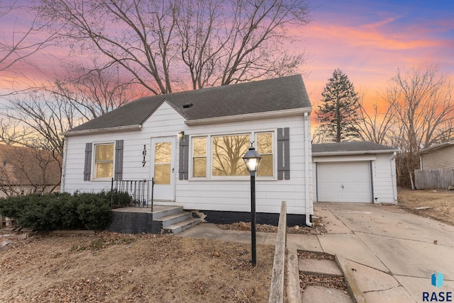 bungalow-style house featuring a garage, roof with shingles, and driveway