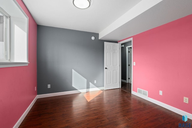 empty room with baseboards, visible vents, and wood finished floors