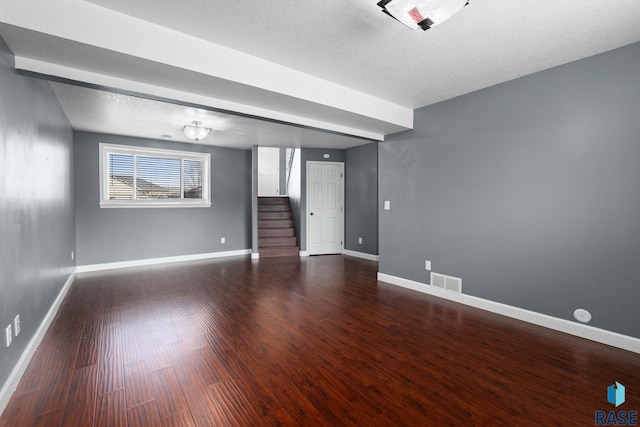 empty room with baseboards, stairs, visible vents, and wood finished floors