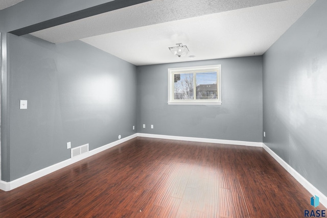 unfurnished room featuring visible vents, a textured ceiling, baseboards, and wood finished floors