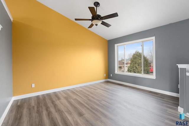 spare room with lofted ceiling, wood finished floors, visible vents, and baseboards