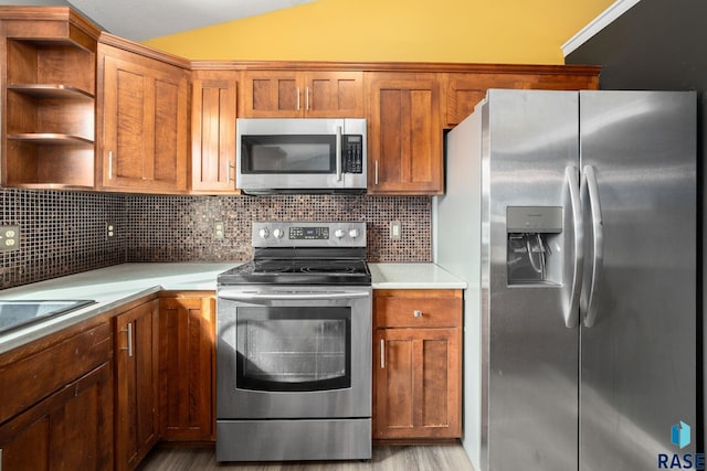 kitchen with stainless steel appliances, lofted ceiling, light countertops, backsplash, and brown cabinetry