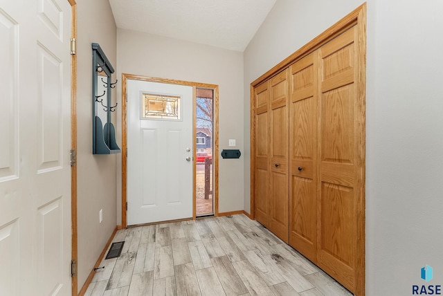 foyer entrance featuring light wood finished floors, visible vents, and baseboards