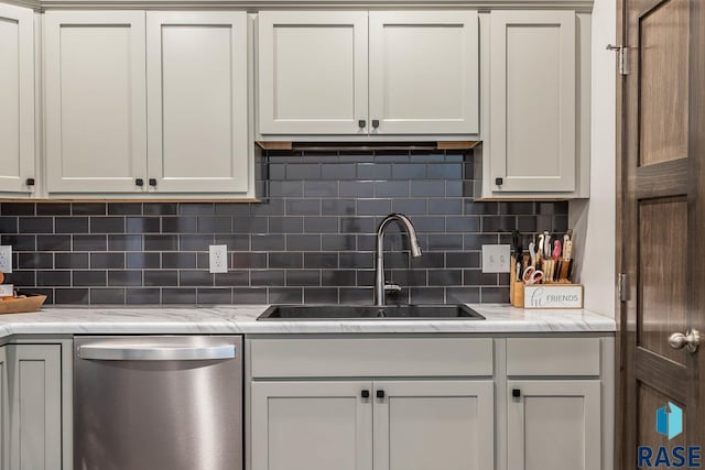 kitchen featuring a sink, light stone countertops, decorative backsplash, and stainless steel dishwasher