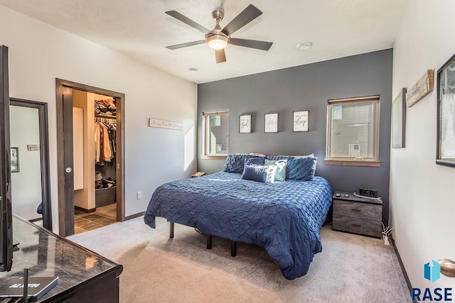 bedroom with baseboards, a ceiling fan, a walk in closet, carpet flooring, and a closet