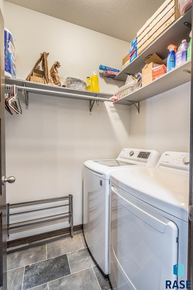 washroom with laundry area, a textured ceiling, and independent washer and dryer