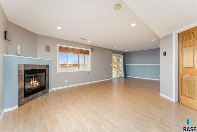 unfurnished living room featuring recessed lighting, baseboards, light wood-style flooring, and a tiled fireplace