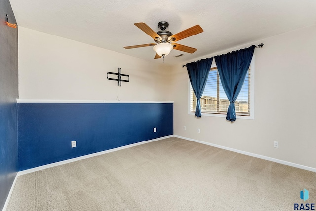 spare room featuring carpet flooring, ceiling fan, visible vents, and baseboards