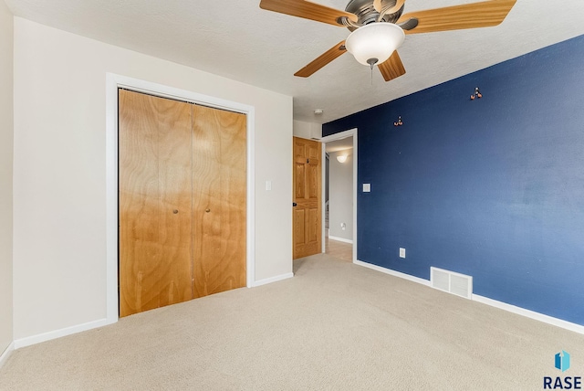 unfurnished bedroom with baseboards, visible vents, ceiling fan, carpet floors, and a closet