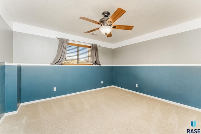 carpeted spare room featuring a textured ceiling, a ceiling fan, visible vents, and baseboards