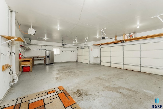 garage with a garage door opener and stainless steel fridge with ice dispenser