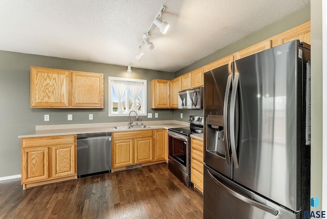 kitchen with a textured ceiling, stainless steel appliances, a sink, light countertops, and dark wood finished floors