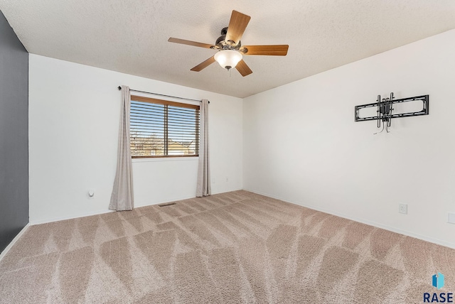 carpeted spare room with a textured ceiling and ceiling fan