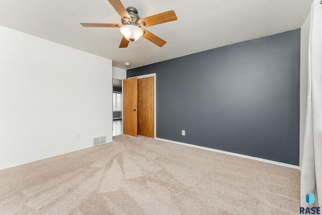 spare room with baseboards, carpet, visible vents, and a textured ceiling