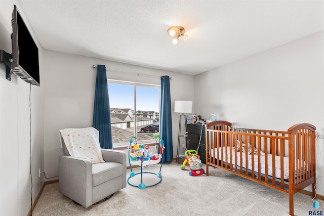 carpeted bedroom featuring a crib, baseboards, and a textured ceiling