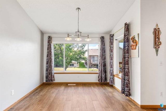 unfurnished dining area with lofted ceiling, wood finished floors, and baseboards