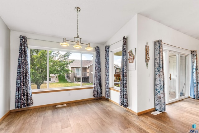 unfurnished dining area with lofted ceiling, visible vents, baseboards, and wood finished floors